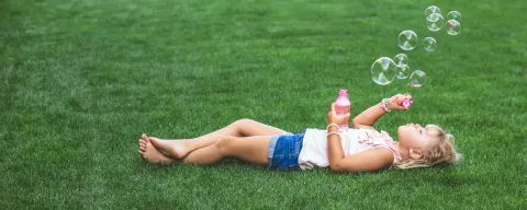girl laying in grass blowing bubbles